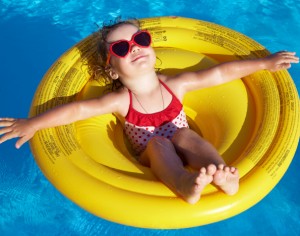 Funny little girl swims in a pool in an yellow life preserver