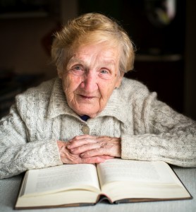 Grandmother sitting at the table with a big book.